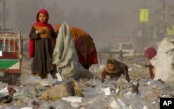 FILE - Afghan refugee girls collect recyclable goods from garbage to sell and earn a living for their families in Peshawar, Pakistan, Feb. 5, 2016.