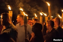 FILE - White supremacists carry torches on the grounds of the University of Virginia, on the eve of a planned "Unite the Right" rally in Charlottesville, Virginia, Aug. 11, 2017.