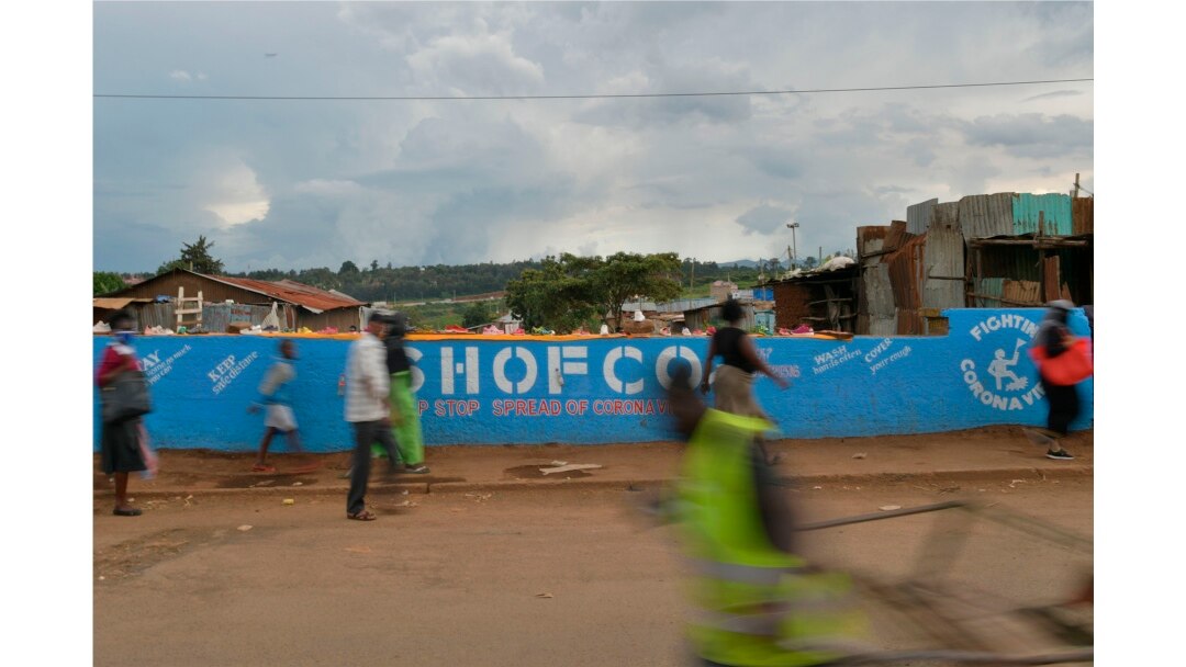 People walk across a bridge with a message written on the barriers advocating personal efforts to stem the spread of the COVID-19 coronavirus in the Kibera slum, Nairobi, on April 14, 2020.