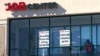 FILE - A man walks past signs posted at an employment agency, in Manchester, New Hampshire, March 2, 2021. 