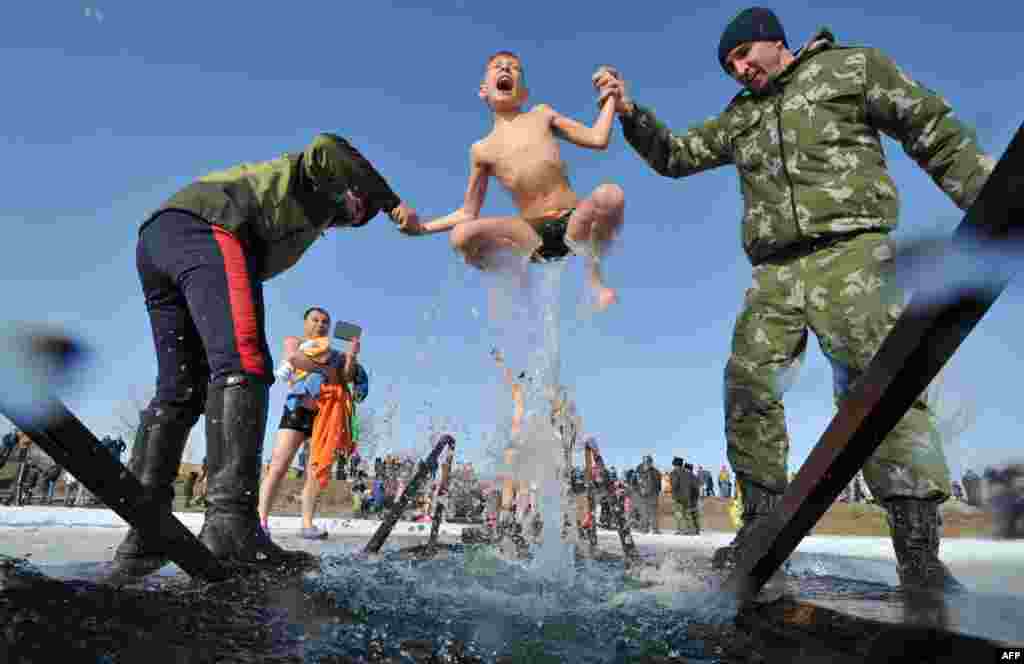 Cossacks help a boy to take a bath in the icy waters of a lake during the celebration of the Epiphany holiday near the village of Leninskoe, some 15 km of Bishkek, Kyrgyzstan.