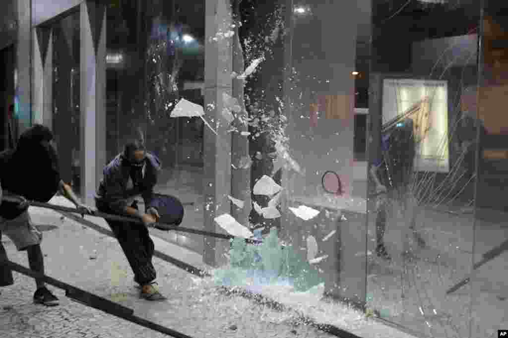 Protesters shatter the glass walls of a bank during a demonstration against proposed reforms by the federal government, in Rio de Janeiro, Brazil, March 15, 2017.