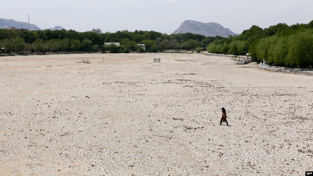 An Iranian girl walks across the Zayandeh Rud river in Isfahan, now dry because of water extraction before it reaches the city, April 11, 2018.