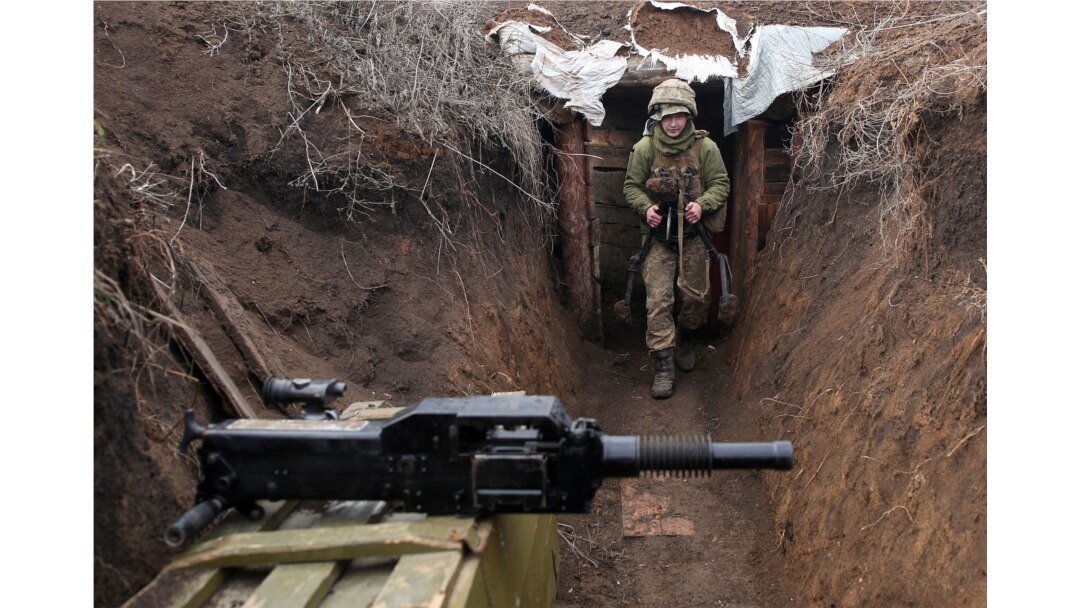 An Ukrainian serviceman walks in a trench as he stands at his post on the frontline with Russia backed separatists near the town of Zolote, in the Lugansk region on April 8, 2021.
