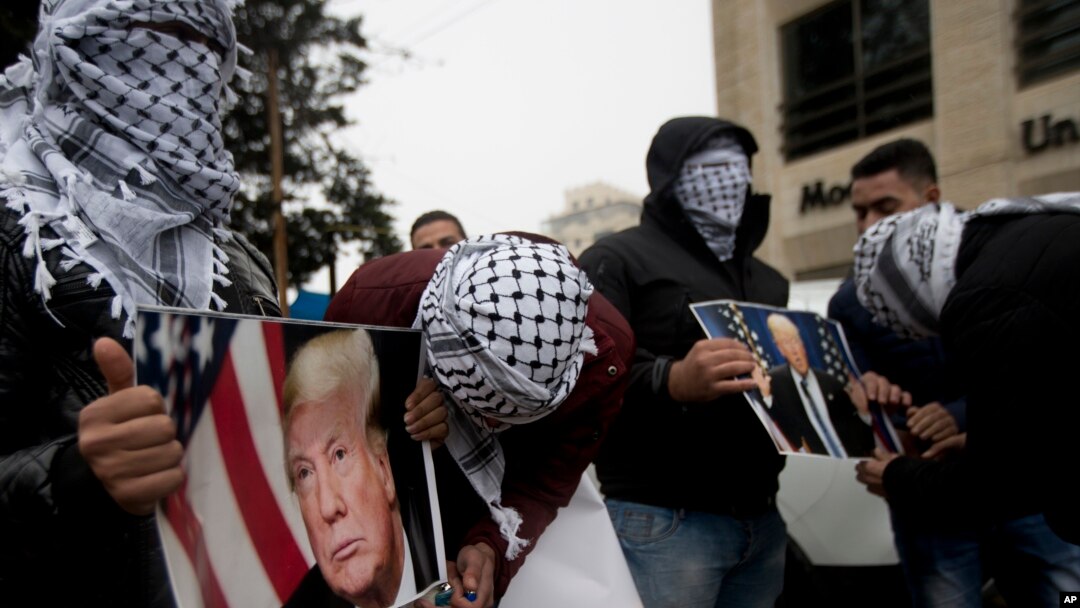 Palestinians holds posters of the U.S. President Donald Trump during a protest in the West Bank City of Ramallah, Dec. 6, 2017. 