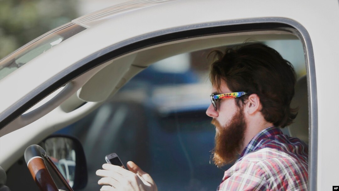 FILE - An man works his phone as he drives through traffic in Dallas, Tuesday, Feb. 26, 2013. Texas lawmakers are considering a statewide ban on texting while driving. (AP Photo/LM Otero)