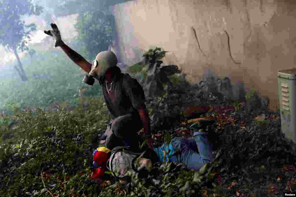 An injured demonstrator is been helped by another after clashing with riot police during the so-called "mother of all marches" against Venezuela's President Nicolas Maduro in Caracas.