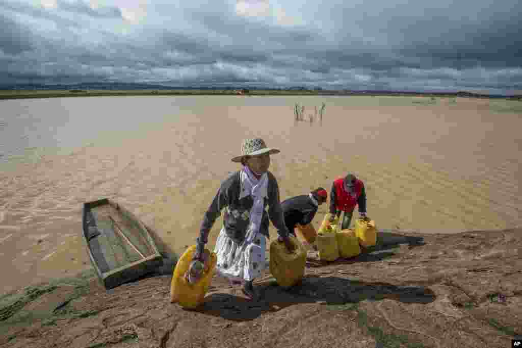 Residents cross a flooded area in Madagascar's capital Antananarivo, to collect fresh water. Cyclone Enawo hit land Tuesday, claiming the lives of at least five people and forcing some 10,000 people abandon their homes because of storm damage.