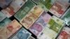 FILE - Turkish liras, center, featuring images of Turkish Republic founder Mustafa Kemal Ataturk, among other foreign currency, Istanbul, June 8, 2015.