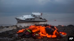 Life Jackets and a boat used by refugees and migrants to cross a part of the Aegean sea from Turkey to the Greek island of Lesbos remain on a beach, Thursday, Nov. 26, 2015.