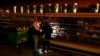 FILE - Customers use a cellphone light to shop in grocery store in Dallas, Feb. 16, 2021. Texas faced power outages after a series of winter storms. U.S. energy was rated at a C grade level Wednesday, and U.S. infrastructure overall received a C-minus.
