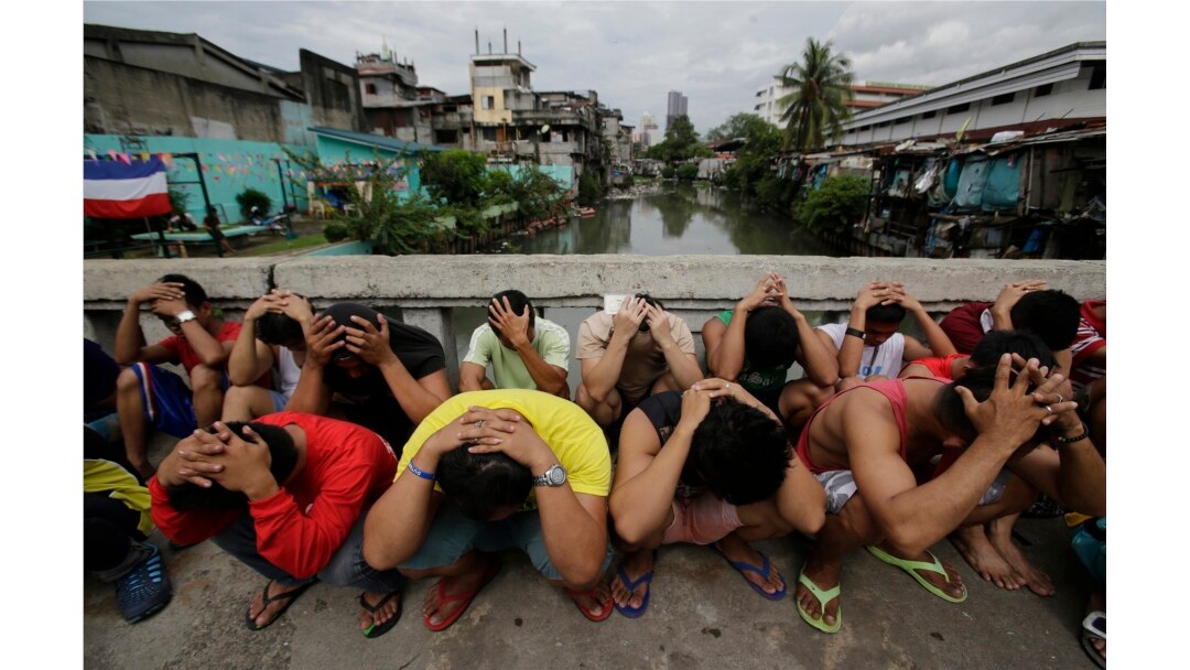 Filipino men place their hands over their heads as they are rounded up during a police operation as part of the continuing "War on Drugs" campaign of Philippine President Rodrigo Duterte in Manila, Philippines, Oct. 7, 2016.