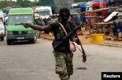 FILE - A mutinying soldier gestures as he stands guard at the checkpoint of the entrance of Bouake, Ivory Coast, May 15, 2017.