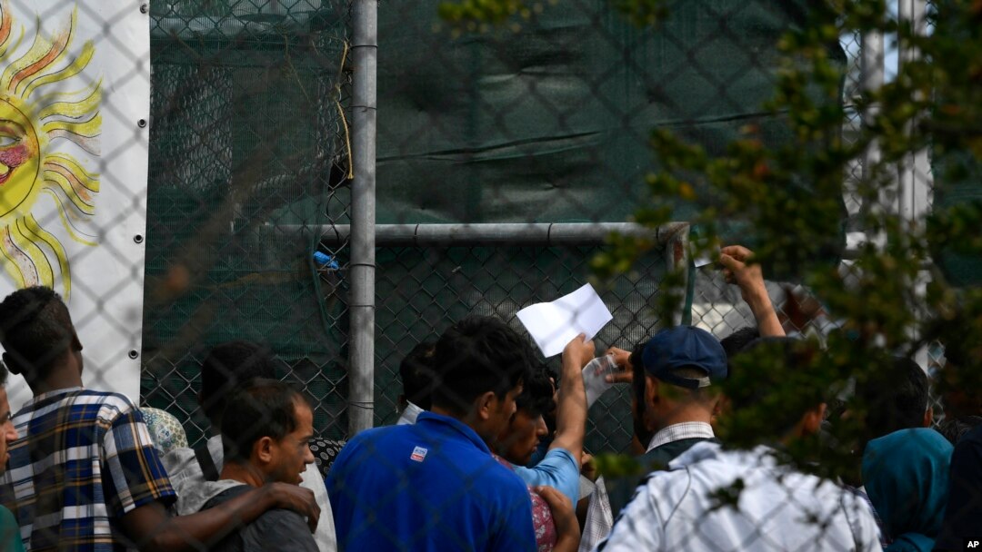 FILE - Migrants and refugees wait in a queue for the doctor at the Moria refugee camp on the northeastern Aegean island of Lesbos, Greece, Sept. 25, 2019. 