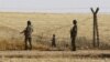 Turkish soldiers stand guard as a Syrian refugee boy waits behind the border fences to cross into Turkey on the Turkish-Syrian border, near the southeastern town of Akcakale in Sanliurfa province, Turkey, June 5, 2015.