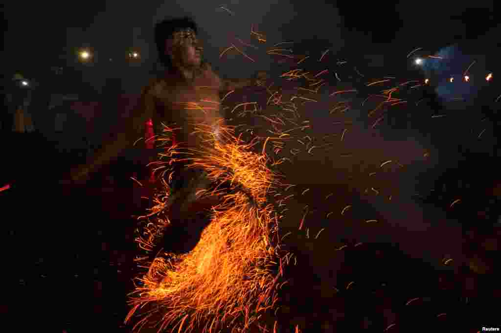 A Balinese Hindu runs through burning coconut husks during a "Mesabatan Api" ritual on the eve of Nyepi, a day of silence for self-reflection to celebrate the new year, in Gianyar, Bali, Indonesia.