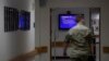 FILE - A member of the U.S. Army walks down the hall toward a monitor displaying COVID-19 safety information in Fort Meade, Md., March 25, 2020.