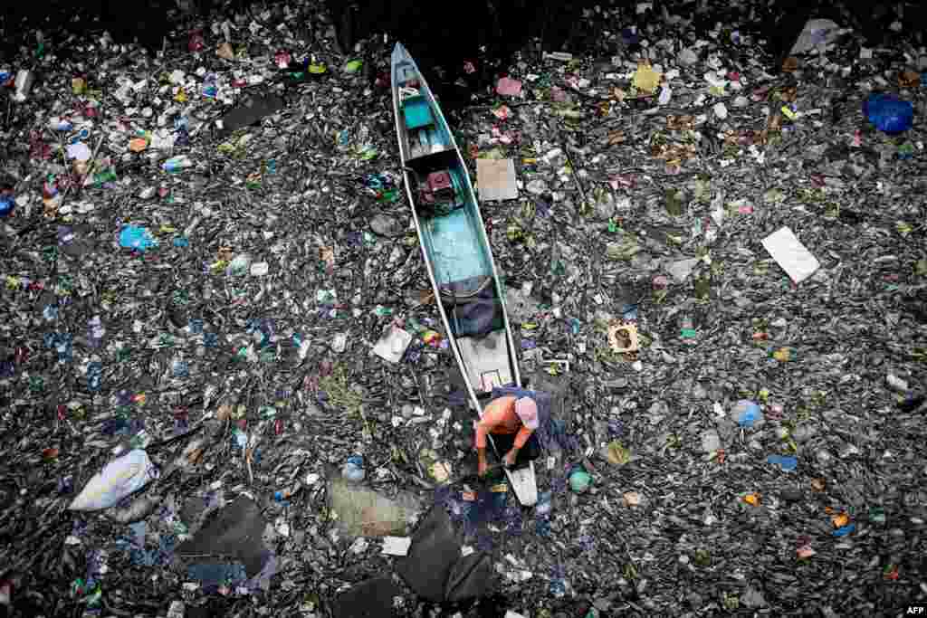A worker collects garbage from the Marilao River in Bulacan, north of Manila, the Philippines.