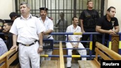 Police guard Egyptian activist Ahmed Douma (C), who is seen behind bars, during his trial at the New Cairo court, on the outskirts of Cairo, Egypt, June 3, 2013.