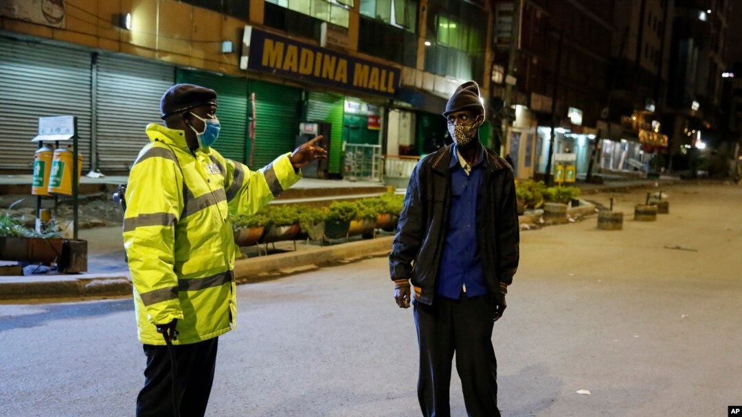 FILE - A Kenyan police officer stops a man who was heading home past the start of the daily dusk-to-dawn curfew in the Eastleigh area of Nairobi, Kenya.