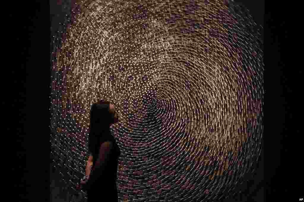 A Christie's auction house employee poses for photographs next to one part of German Sculptor's Guenther Uecker's "Spirale I, Spirale II (Doppelspirale)" in London. The piece is estimated to fetch 1 to 1.5 million pounds ($1.2 to $1.8 million, 1.1 to 1.7 million euro) in an evening auction on March 7.