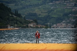 FILE - In this June 16, 2016, photo, artist Christo Vladimirov Javacheff walks on his monumental installation 'The Floating Piers' he created with late Jeanne-Claude during a press preview at the lake Iseo, northern Italy.