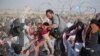 FILE - A Syrian refugee hands a toddler over a broken border fence into Turkey in Akcakale, Sanliurfa province, southeastern Turkey, June 14, 2015.