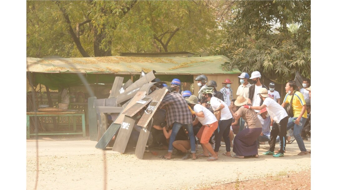Protesters take cover behind shields in Nyaung-U, Myanmar, March 7, 2021, in this still image from a video obtained from social media.