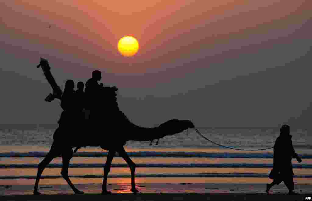 Pakistani tourists ride on a camel during the last sunset of the year at Clifton beach in Karachi.