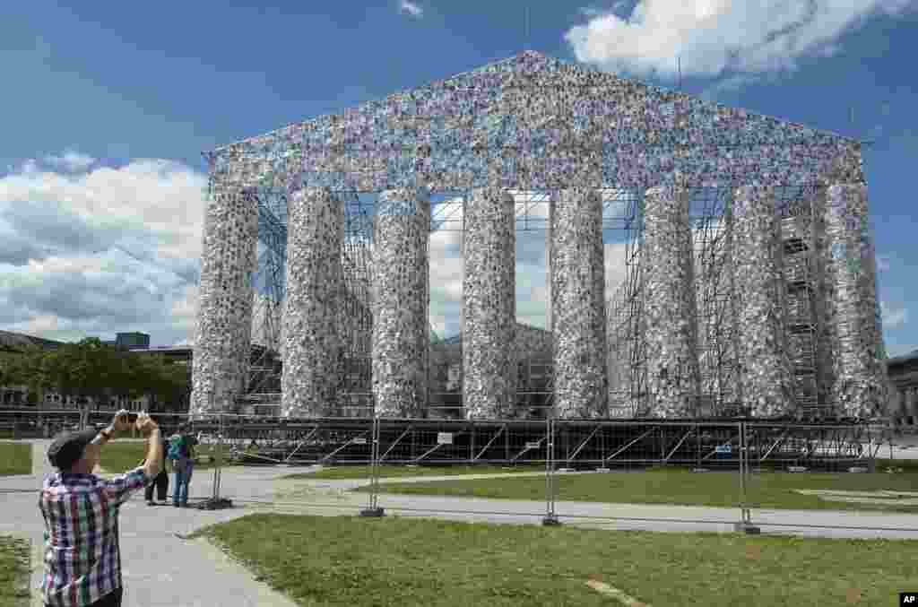A man takes a photo of the art work &#39;The Parthenon of Books&#39; by Argentine&#39;s artist Marta Minujin, which is under construction, in preparation for the upcoming art exhibition in Kassel, Germany.