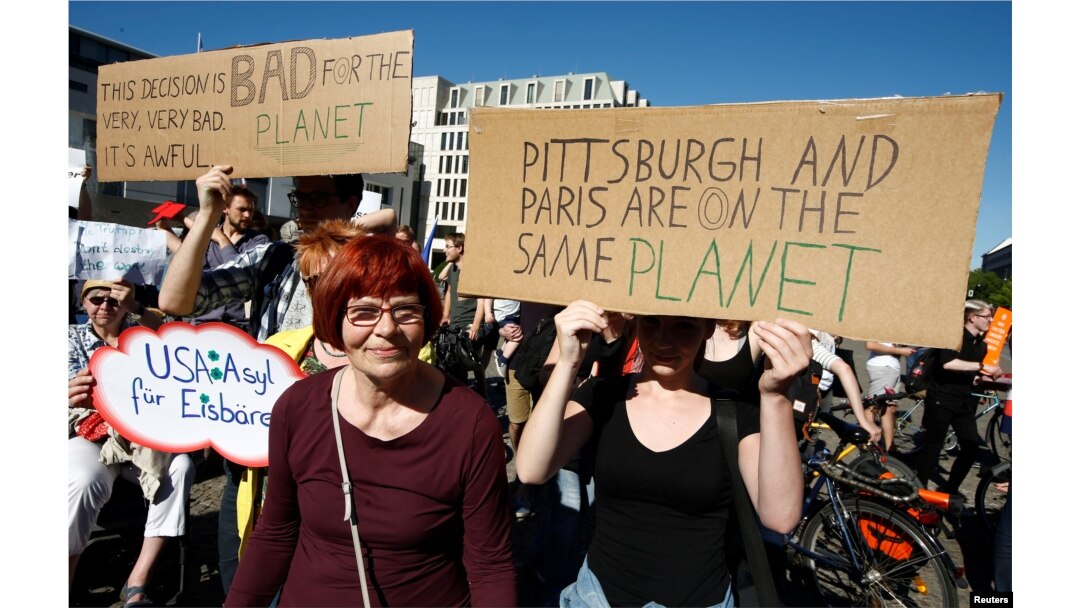 People hold banners as they protest next to the Brandenburg Gate, beside the U.S. embassy, against the U.S. withdrawal from the Paris climate change deal, in Berlin, Germany, June 2, 2017.