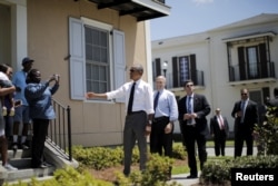 FILE - U.S. President Barack Obama chats with local residents in an area reconstructed after Hurricane Katrina, in New Orleans, La., Aug. 27, 2015. At his side is New Orleans Mayor Mitch Landrieu.