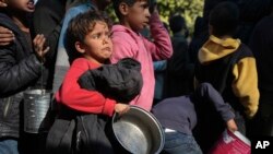 FILE - Palestinian children queue for food in Deir al-Balah, Gaza Strip, Dec. 13, 2024.
