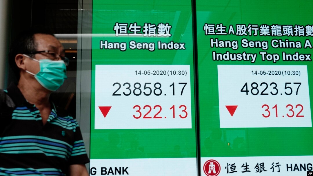 A man wearing face mask walks past a bank electronic board showing the Hong Kong share index at Hong Kong Stock Exchange, May 14, 2020.
