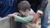 Syrians help an injured child following an alleged airstrike by government forces near a school in the northern Syrian city of Aleppo, Jan. 21, 2014. 