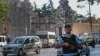 A Turkish police officer secures the road that leads to Istanbul's Dolmabahce Palace, background, Aug. 19, 2015, following an armed attack.