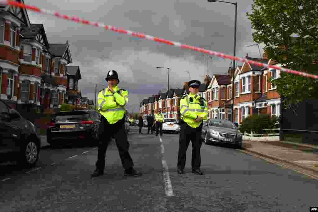 British police officers secure a cordon in a residential street in north-west London where firearms officers shot a female subject after they carried out a specialist entry into an address.