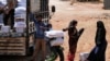 FILE - A worker holds bags and a box of humanitarian aid in the opposition-held Idlib, Syria June 9, 2021.