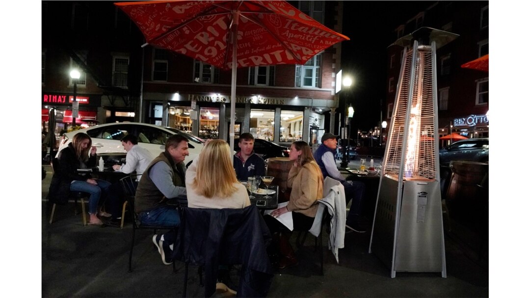 Diners have dinner outdoors, Nov. 6, 2020, in Boston's North End. More stringent coronavirus restrictions are now in effect in Massachusetts, including requiring restaurants to stop providing table service at 9:30 p.m.