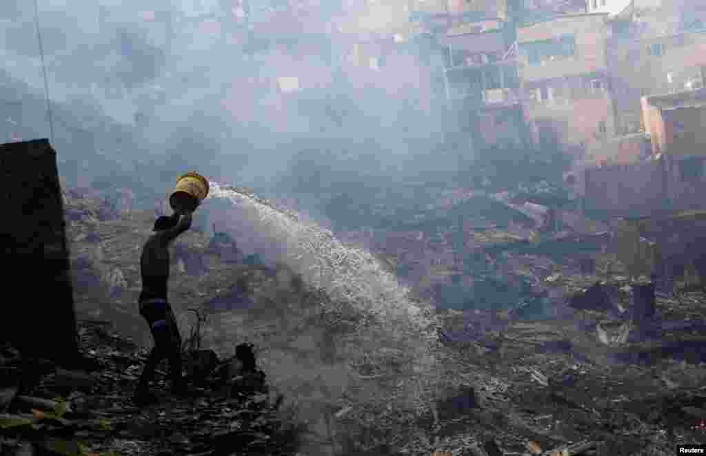 A resident pours water to extinguish a fire at Paraisopolis slum in Sao Paulo, Brazil, March 1, 2017.