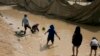 FILE - children play in a mud puddle in the section for foreign families at Al-Hol camp in Hasakeh province, Syria.