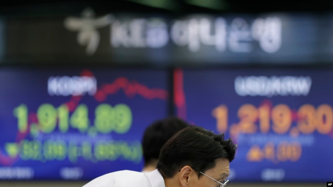 A currency trader watches the computer monitors near the screens showing KOSPI, left, and the foreign exchange rate between the U.S. dollar and South Korean won at the foreign exchange dealing room in Seoul, South Korea, Aug. 6, 2019.