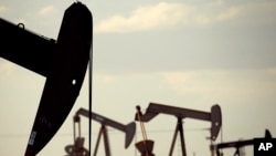 FILE - Pumpjacks work in a field near Lovington, N.M., April 24, 2015.