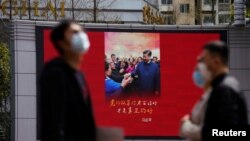 资料照片: 上海行人走过一个显示中国领导人习近平的大屏幕。(2020年3月23日)