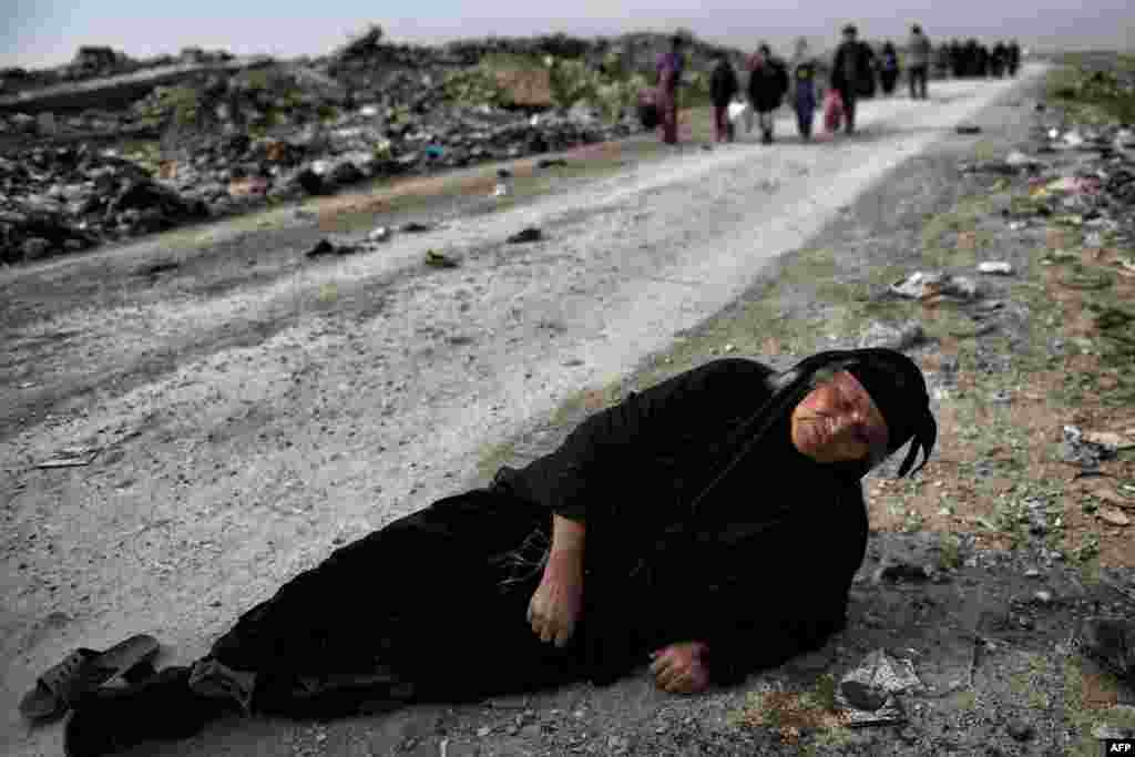 A woman lies on the ground while civilians flee Mosul as Iraqi forces advance inside the city, during fighting against Islamic State militants.