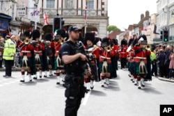 Armed police stand guard as the Royal Regiment of Scotland band march by in Windsor, south England, May 7, 2019, a day after Prince Harry announced that his wife Meghan, Duchess of Sussex, had given birth to a boy.