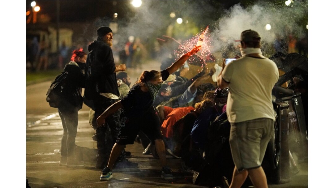 A protester tosses an object toward police during clashes outside the Kenosha County Courthouse late Tuesday, Aug. 25, 2020, in Kenosha, Wis., on third night of unrest following the shooting of a Black man, Jacob Blake.