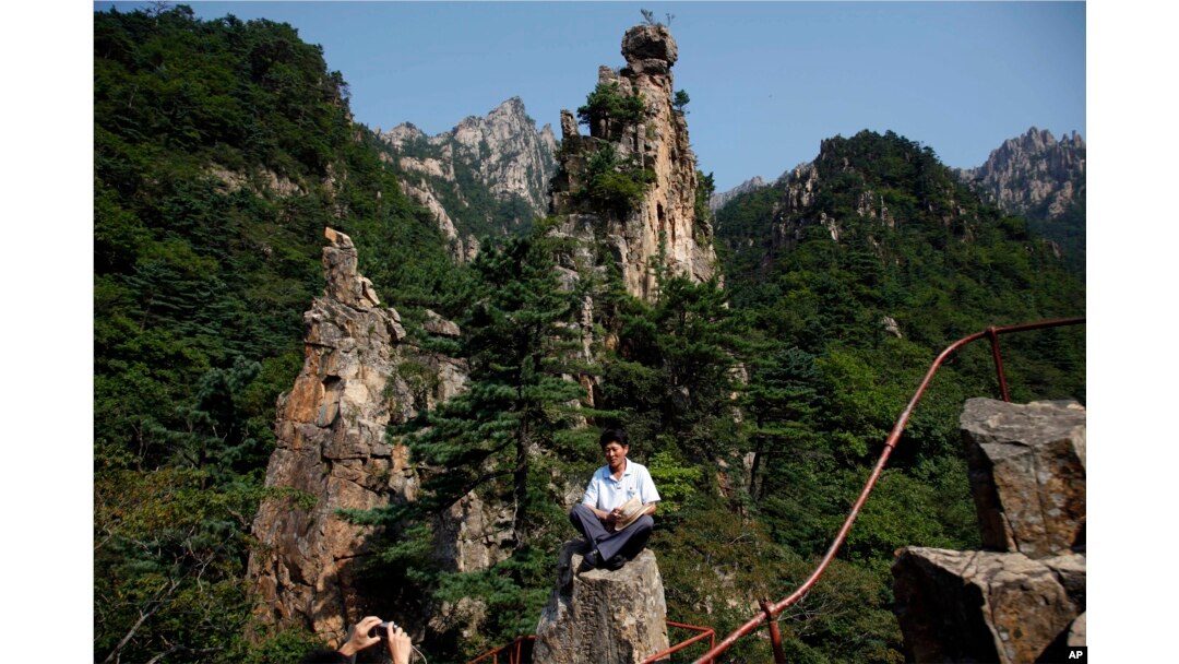 FILE - A North Korean guide poses for photos among the peaks of the Mount Kumgang resort, also known as Diamond Mountain, in North Korea, Sept. 1, 2011. South Korea's Moon Jae-in is look at ways to build relations with North Korea, including resuming tours.