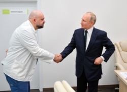 Russian President Vladimir Putin, right, shakes hands with the hospital's chief Denis Protsenko during his visit to the hospital for coronavirus patients, March 24, 2020.