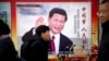 FILE - People walk past a propaganda billboard showing Chinese President Xi Jinping on a street in Beijing, China, March 2, 2018.